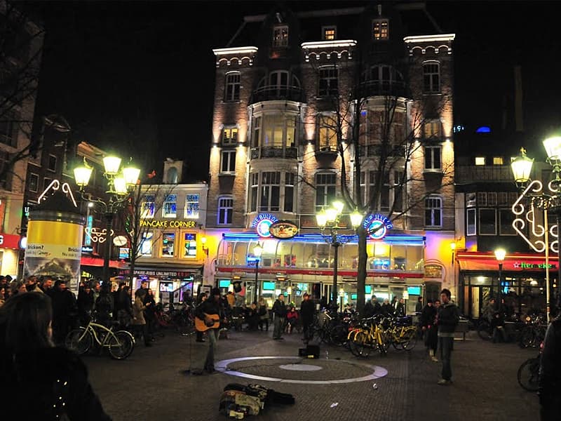 Fotografia del quartiere Leidsplein di Amsterdam di sera con le luci accese e persone