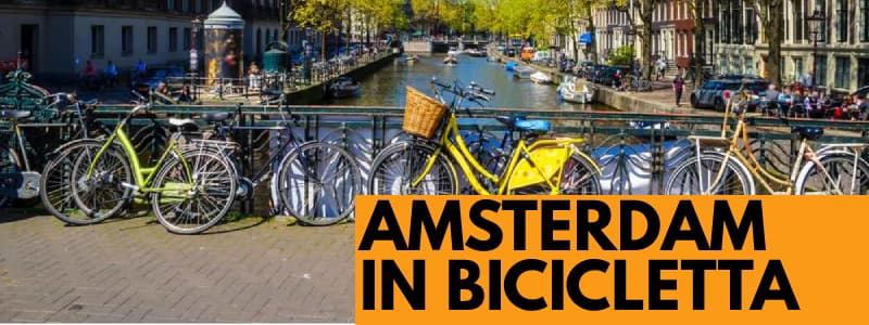 Fotografia di alcune biciclette legate al ponte di un canale di Amsterdam con rettangolo in basso a destra arancione con scritta nera Amsterdam in bicicletta