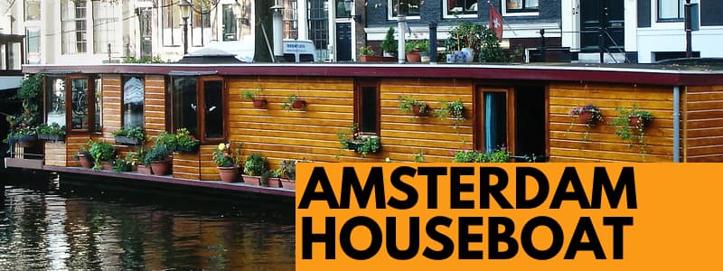 Casa galleggiante in legno sul canale di Amsterdam con rettangolo arancione in basso a destra con scritta nera Amsterdam Houseboat