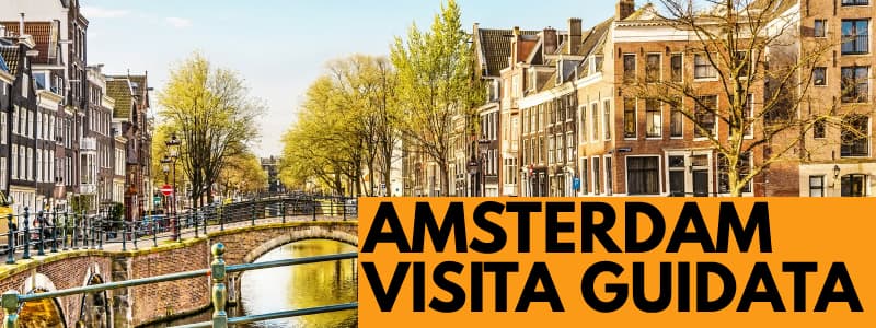 Fotografia di un canale di Amsterdam di giorno con edifici sulla destra, alberi sullo sfondo ed un ponte al centro. In basso a destra rettangolo arancione con scritta nera Amsterdam Visita Guidata